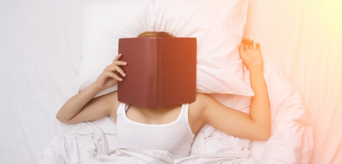 woman on a bed with book over her face