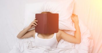 woman on a bed with book over her face