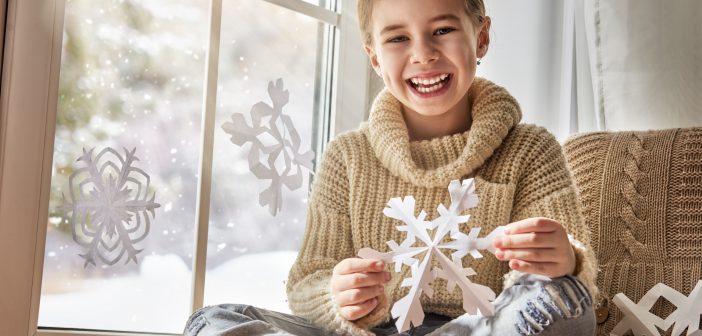 child with a handmade paper snowflake