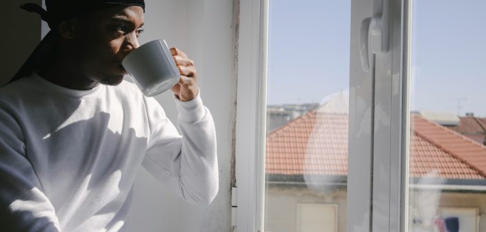 Loneliness stock photo, man drinking coffee at a window