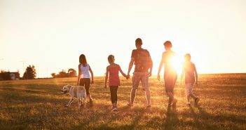 family with dog walking at sunset