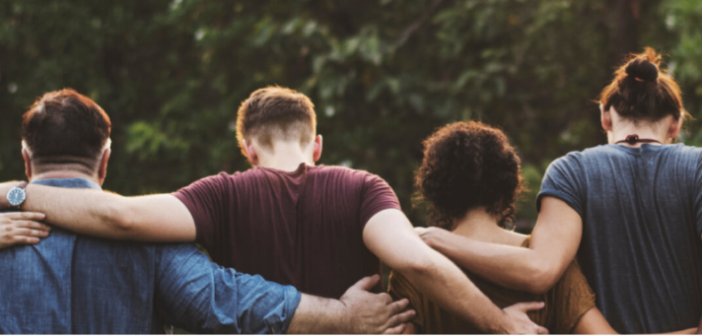 rear view of people with their arms around each other working or volunteering