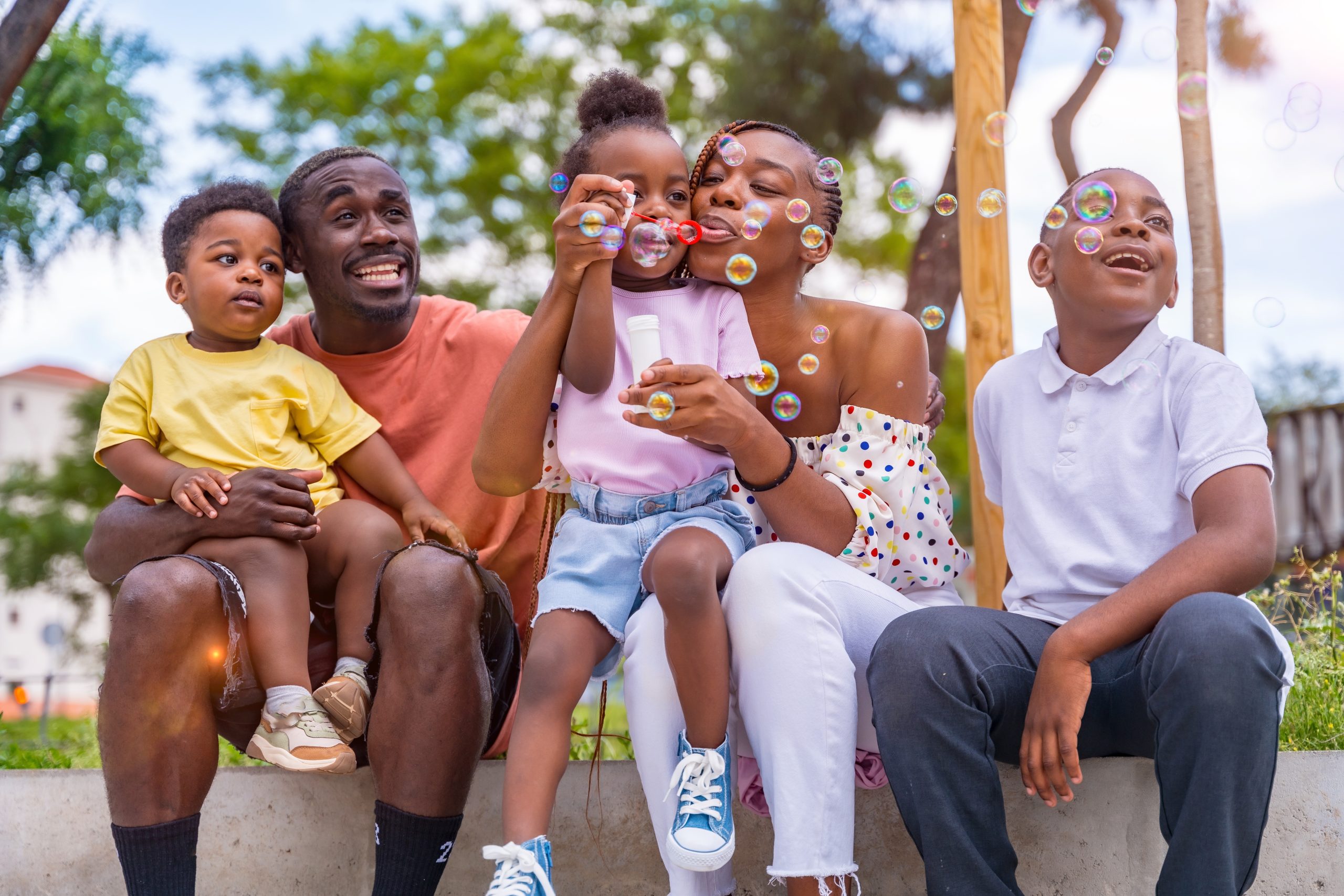 African,Black,Ethnic,Family,With,Children,In,Playground,Blowing,Soap