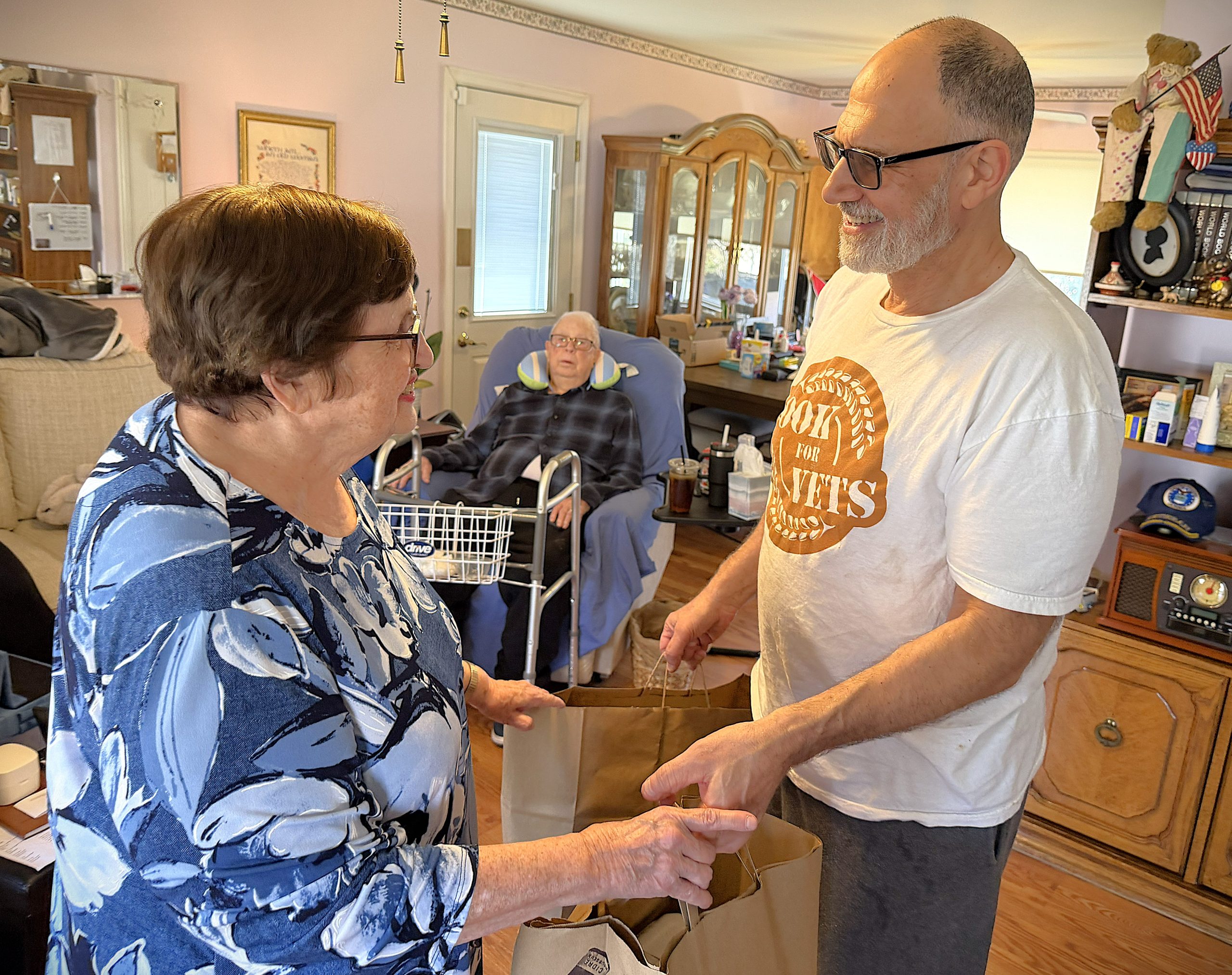 A volunteer hands groceries to a veteran